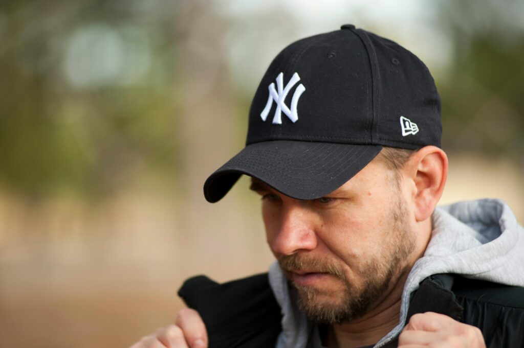 pexels photo 1007804 1007804 Close-up portrait of a man in a black New York Yankees cap outdoors, focusing on his face.