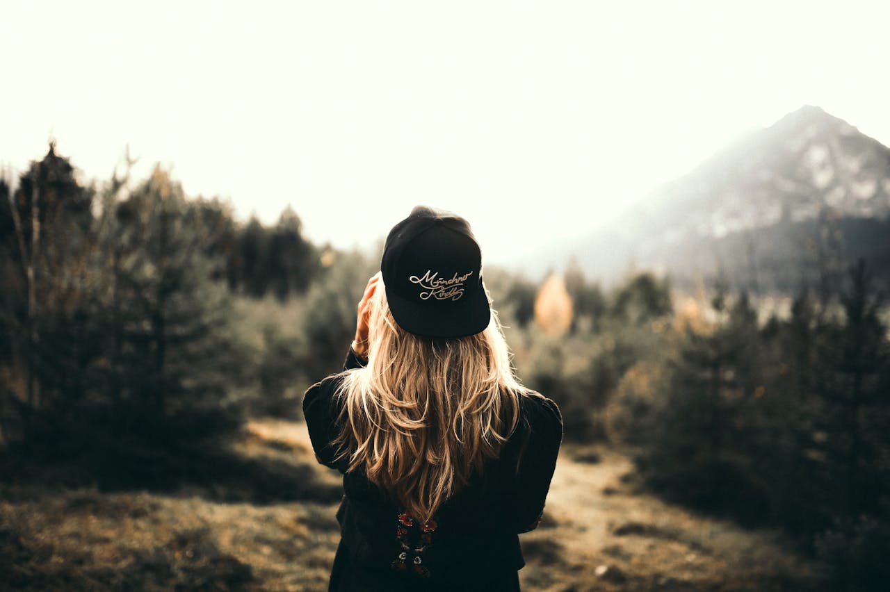 our-services-1 A woman in black cap and sweater enjoys a mountain view, embracing outdoor adventure.